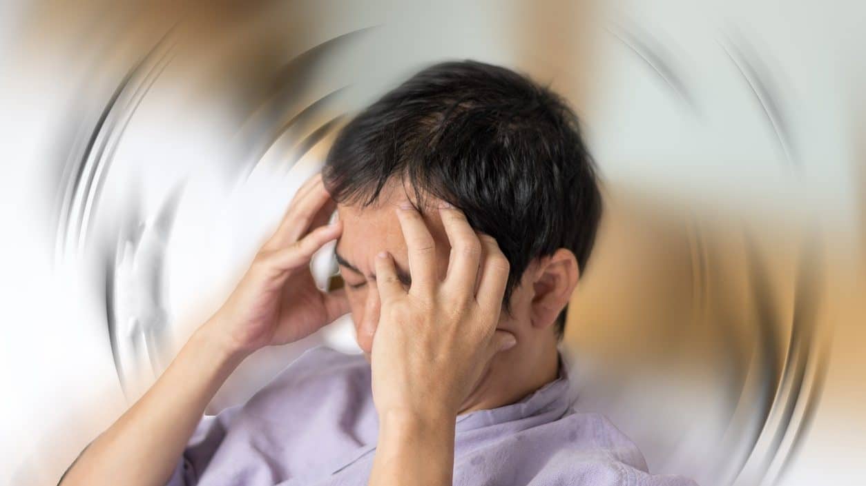 Vertigo illness concept. Man hands on his head felling headache dizzy sense of spinning dizziness,a problem with the inner ear, brain, or sensory nerve pathway.