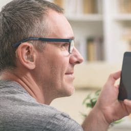 Man with a hearing aid uses his smartphone.
