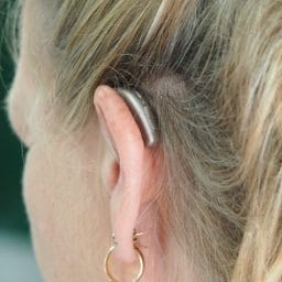 A close-up of a woman with a hearing aid.