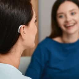 Woman with a hearing aid talking with her friend at home.