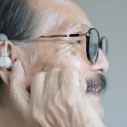 Man holds hand to hearing aid