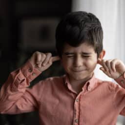 Child putting his fingers in his ears
