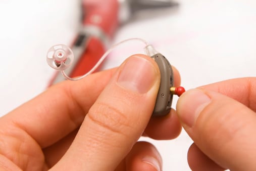 An audiologist adjusting a hearing aid.
