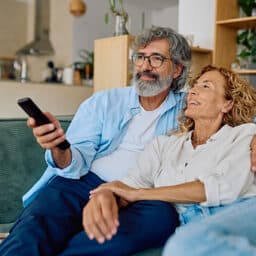 Happy senior couple enjoying quality time together while watching television in their cozy living room.
