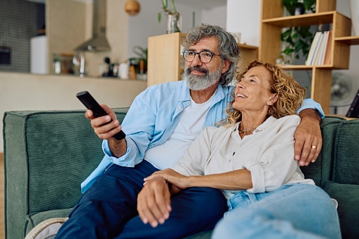 Happy senior couple enjoying quality time together while watching television in their cozy living room.