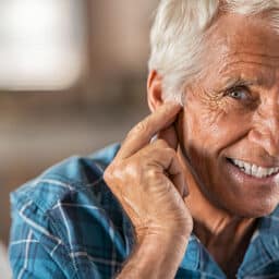 Senior man touching his ear with a hearing aid.