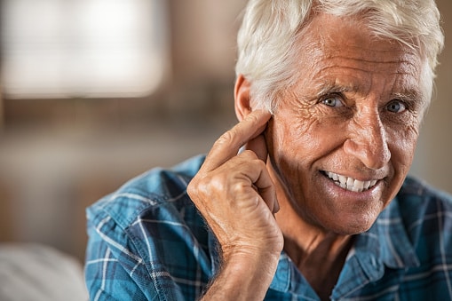 Senior man touching his ear with a hearing aid.